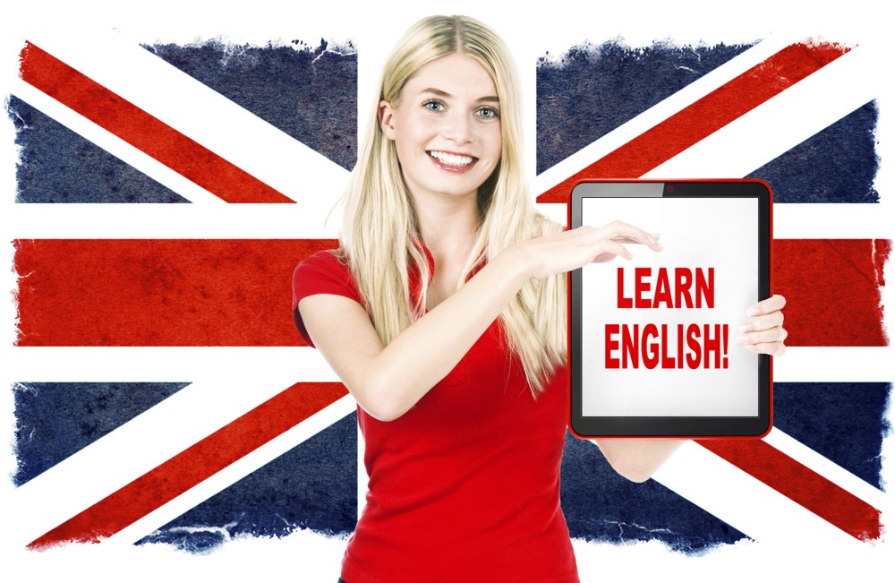 young woman holding tablet pc on the background with british national flag. english learning concept